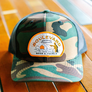 A camo trucker cap with a patch depicting a fisherman, that says, "Boulevard Brewing Company, Since 1989, Beer & Tackle".