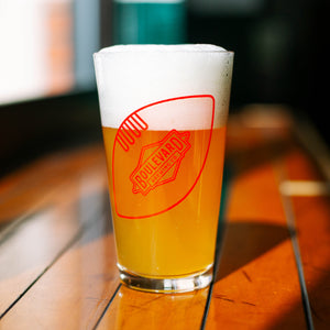 A pint glass full of light beer with a red image of a football with the diamond boulevard logo
