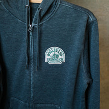 Load image into Gallery viewer, An angled view of the cream patch on a heather grey zip-up hoodie.
