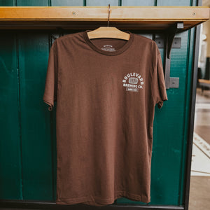 The front of a brown t-shirt, that says, "Better with Age, Boulevard Brewing Co., Barrel-Aged Series" in a white font, hanging up.