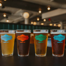 Load image into Gallery viewer, All four styles of pint glasses in a row and full of beer
