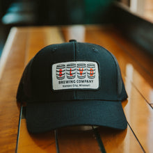 Load image into Gallery viewer, A black trucker cap with a white patch, spelling BLVD out in barrels.
