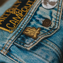 Load image into Gallery viewer, A flame- shaped enamel pin on a jean jacket.
