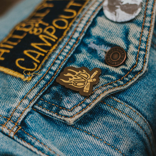 A flame- shaped enamel pin on a jean jacket.