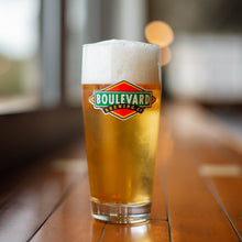 Load image into Gallery viewer, A tall glass full of light beer featuring the classic boulevard diamond logo
