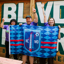 Load image into Gallery viewer, Three people holding a Boulevard Brewing Co flag in front of a wooden wall with 'BLVD' branding.
