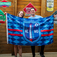 Load image into Gallery viewer, Two people holding a Boulevard Brewing Co flag in front of a wooden wall with brewery signs.
