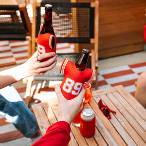 A few hands holding beers dressed in the 89 jersey koolie.