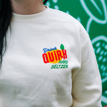 Load image into Gallery viewer, White sweatshirt with 'Drink Quirk Hard Seltzer' logo worn by a person, green background
