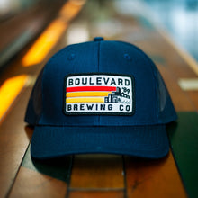 Load image into Gallery viewer, A navy trucker cap with a rectangular patch.
