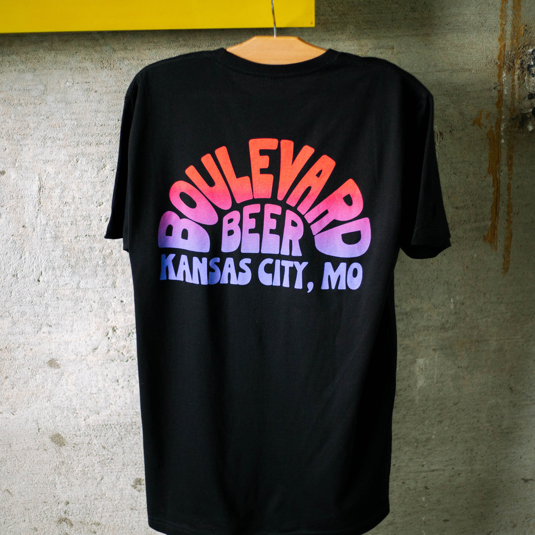 The back of a black t-shirt with a blue, purple, pink, and orange gradient logo.