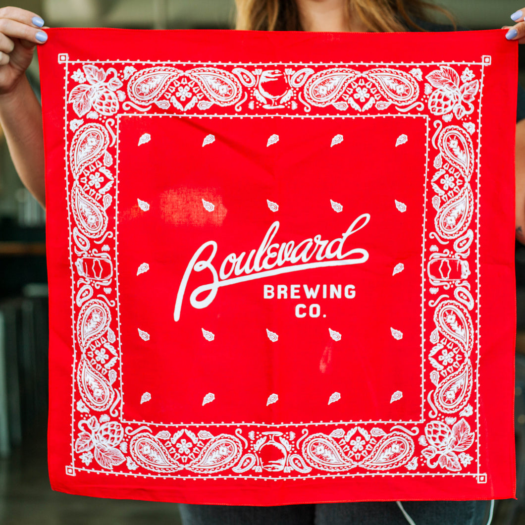 A woman holding up a red and white bandana that says, 
