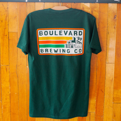 The back of a green t-shirt that says Boulevard Brewing Co. '89 with a picture of the brewery and yellow, orange, and green stripes in a rectangle.