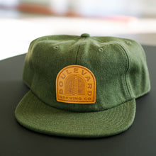 Load image into Gallery viewer, green wool flat brim hat with sewn on &quot;Boulevard Brewing Co.&quot; leather patch
