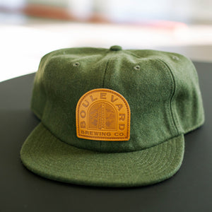 green wool flat brim hat with sewn on "Boulevard Brewing Co." leather patch