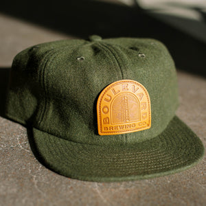 green wool flat brim hat with sewn on "Boulevard Brewing Co" leather patch
