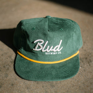 A green corduroy cap on a grey background.