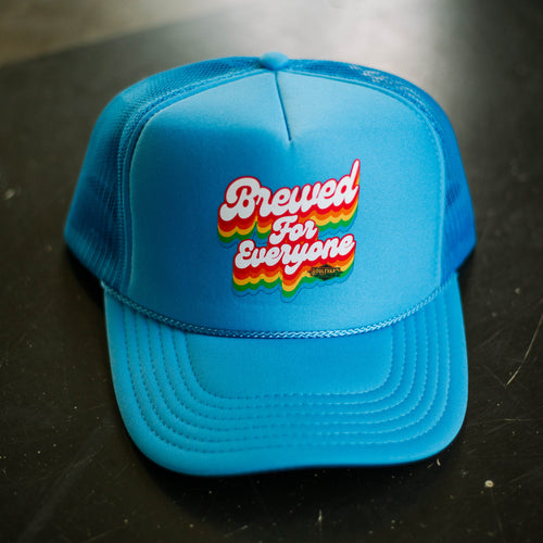 A blue trucker cap made of foam with rainbow lettering that says 