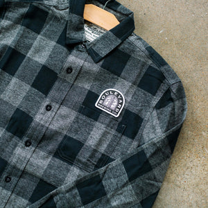 A closeup of the smokestack arch logo on the Arch Lagerman Check Button-Up