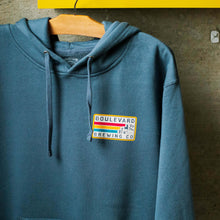 Load image into Gallery viewer, The front of the 89 Retro Rectangle Hoodie with a small front hit of the red, yellow, and blue brewery logo on the upper left side. 
