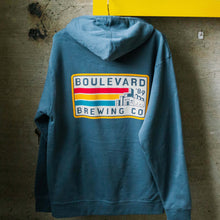 Load image into Gallery viewer, The back of the 89 Retro rectangle hoodie, featuring a dusty blue hoodie with a red, yellow, and blue brewery logo. 
