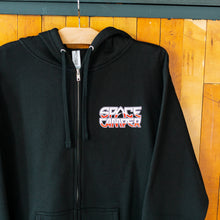Load image into Gallery viewer, Black hoodie with 'Space Camper' logo on a wooden background
