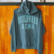 Load image into Gallery viewer, Blue hoodie with 'Boulevard KCMO' text on a wooden background
