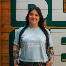Load image into Gallery viewer, Person wearing a light blue t-shirt with 'Boulevard' branding in front of a wooden wall with large green letters.
