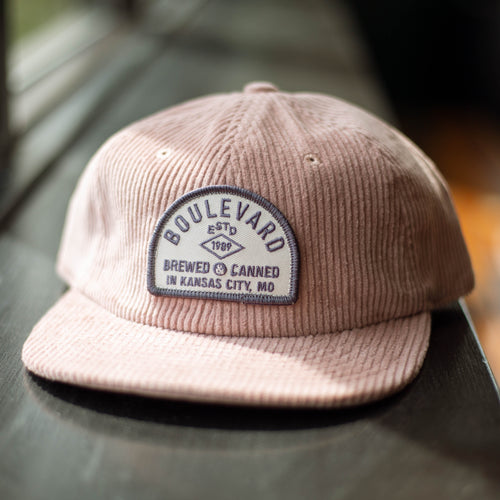 A pink corduroy cap with an arched patch.