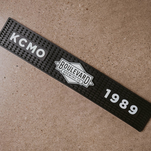 A black bar mat at an angle with a white boulevard diamond logo, KCMO, and 1989 across it.