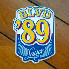 Load image into Gallery viewer, A blue, yellow, red, and white die-cut magnet depicting BLVD &#39;89 Lager.
