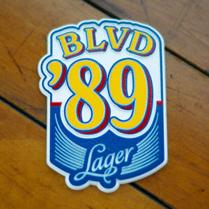 A blue, yellow, red, and white die-cut magnet depicting BLVD '89 Lager.