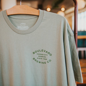 The front of a sage green t-shirt with  small green lettering that says, "Boulevard Brewing Co., Kansas City, Missouri, since 1989".