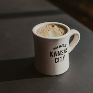 Cream ceramic mug with "Brewed in Kansas City"