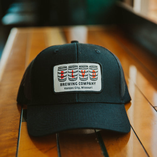 A black trucker cap with a white patch, spelling BLVD out in barrels.