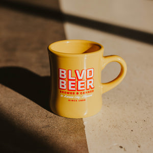 A yellow diner mug that says BLVD BEER