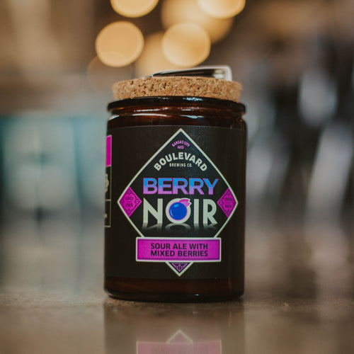 A Berry Noir scented candle against a blurred background.