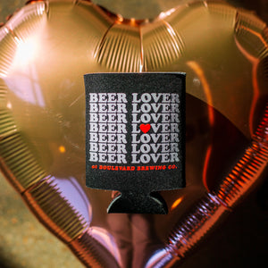 A black koolie with, "Beer Lover" repeated on it, in front of a pink heart-shaped balloon.