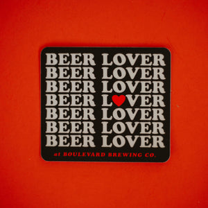 A black sticker with, "Beer Lover" repeated on it, in front of a red background.