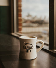 Load image into Gallery viewer, Brewed in KC Mug side with coffee
